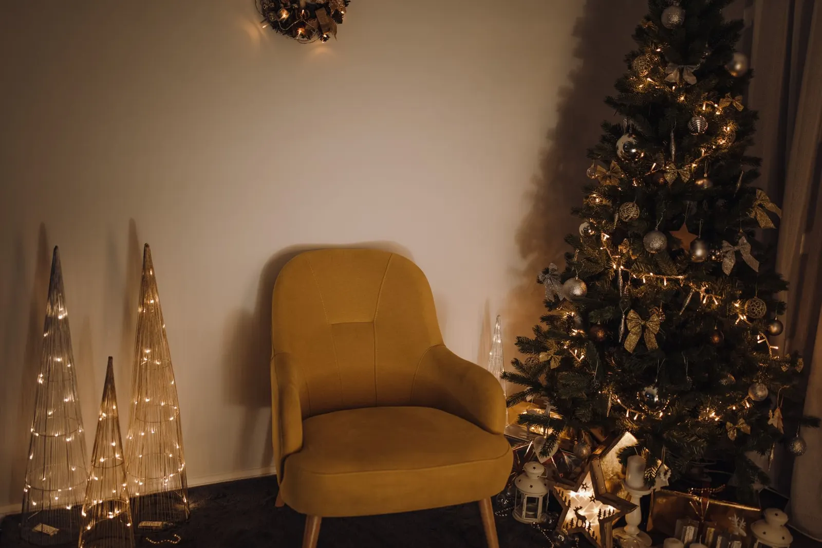 Full green artificial Christmas tree with warm white lights in a cozy living room corner