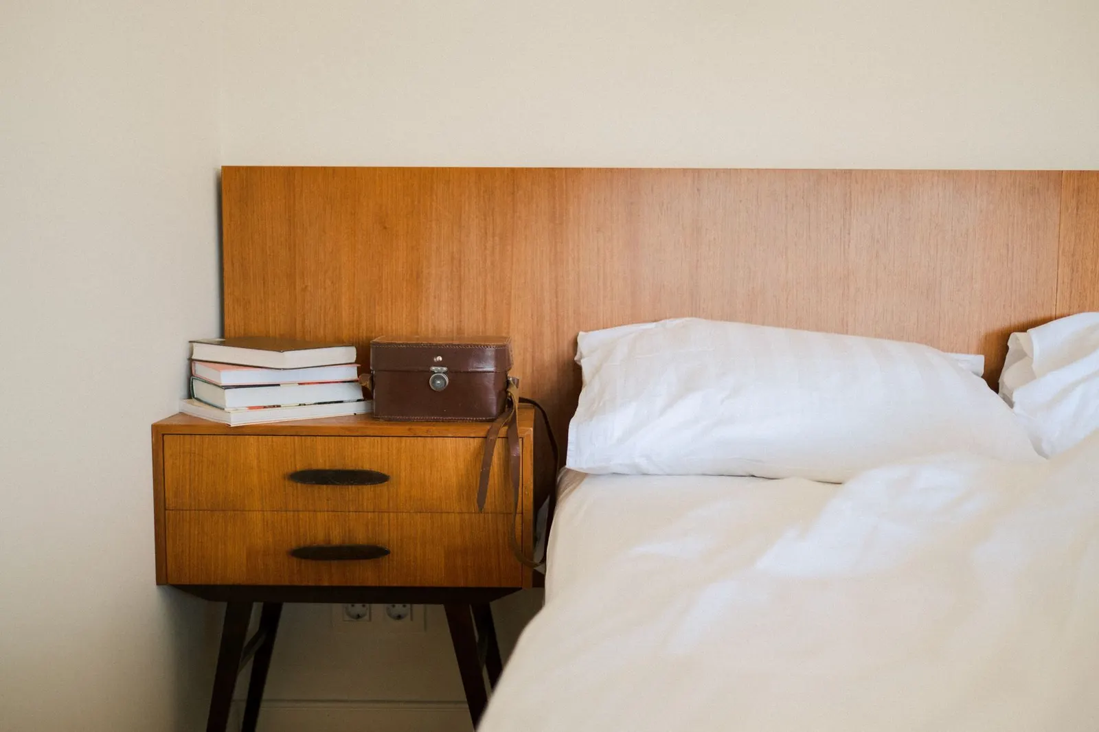 A clean, modern bedroom setup with elegant wooden furniture and books.