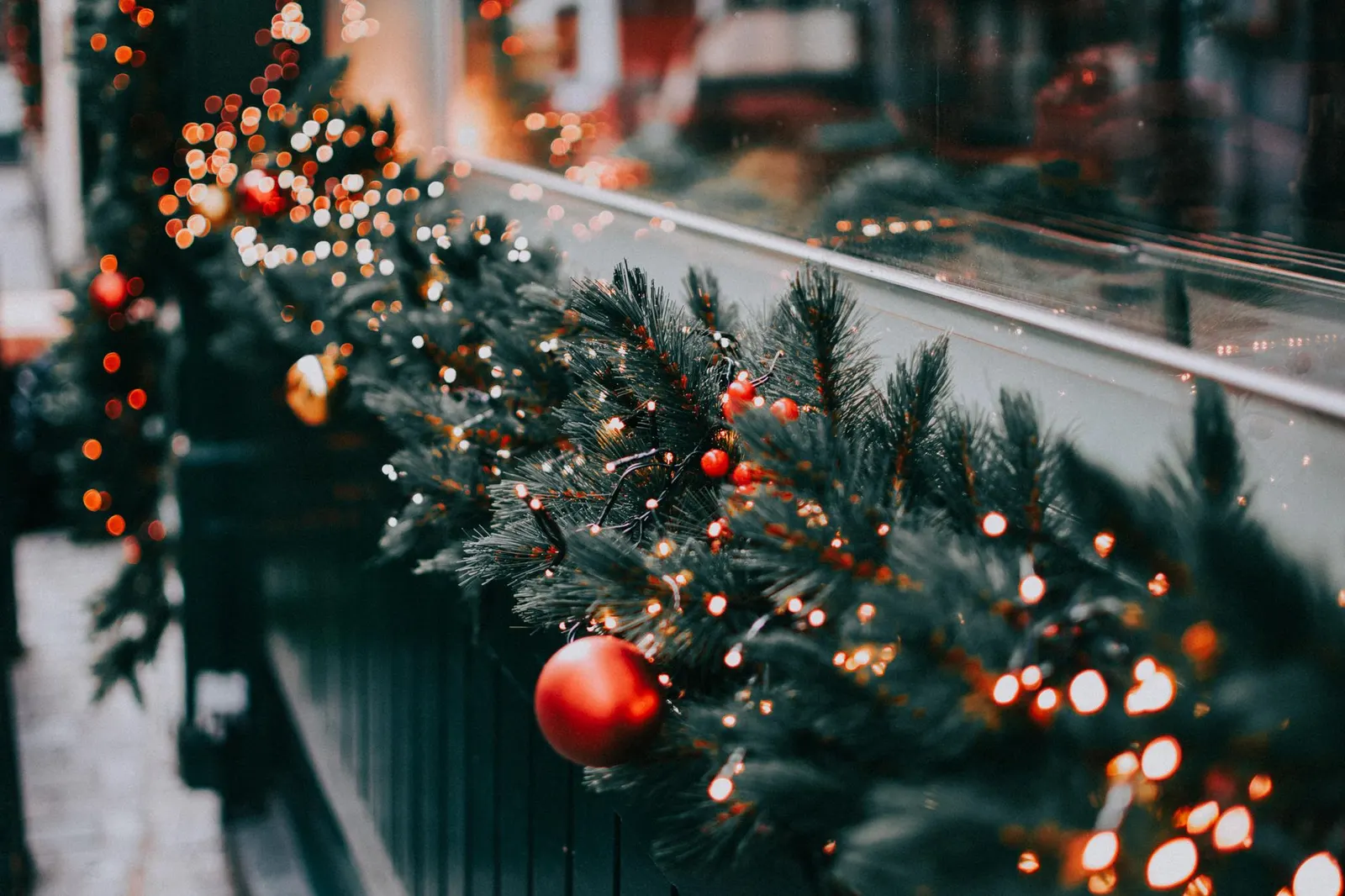 Faux pine garland with warm white lights draped across a tension rod inside an apartment window