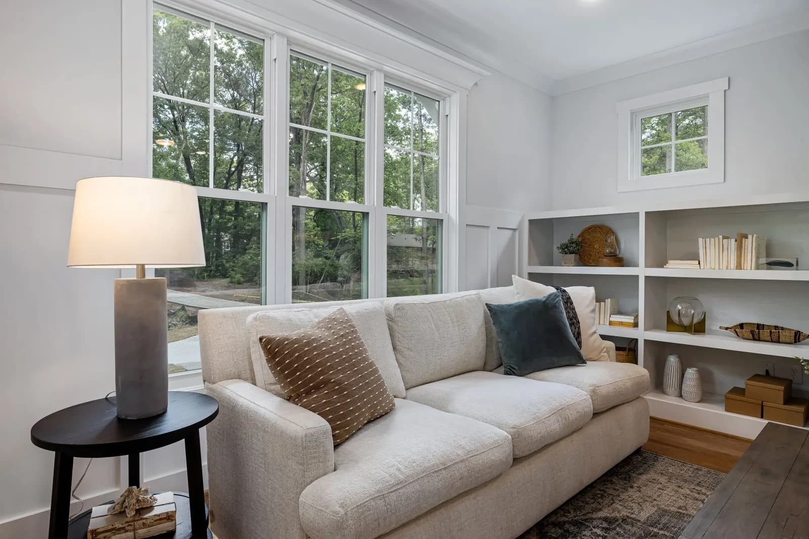 Warm living room with a slipcovered sofa, jute rug, thrifted wood coffee table, floor lamp and linen curtains hung high