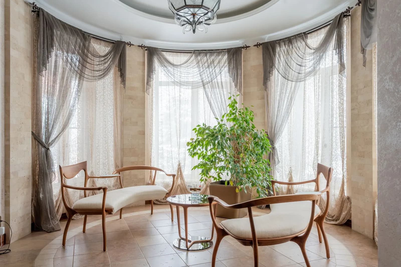 Sunny living room with sheer curtains, a ceiling fan and a cotton rug on a wood floor