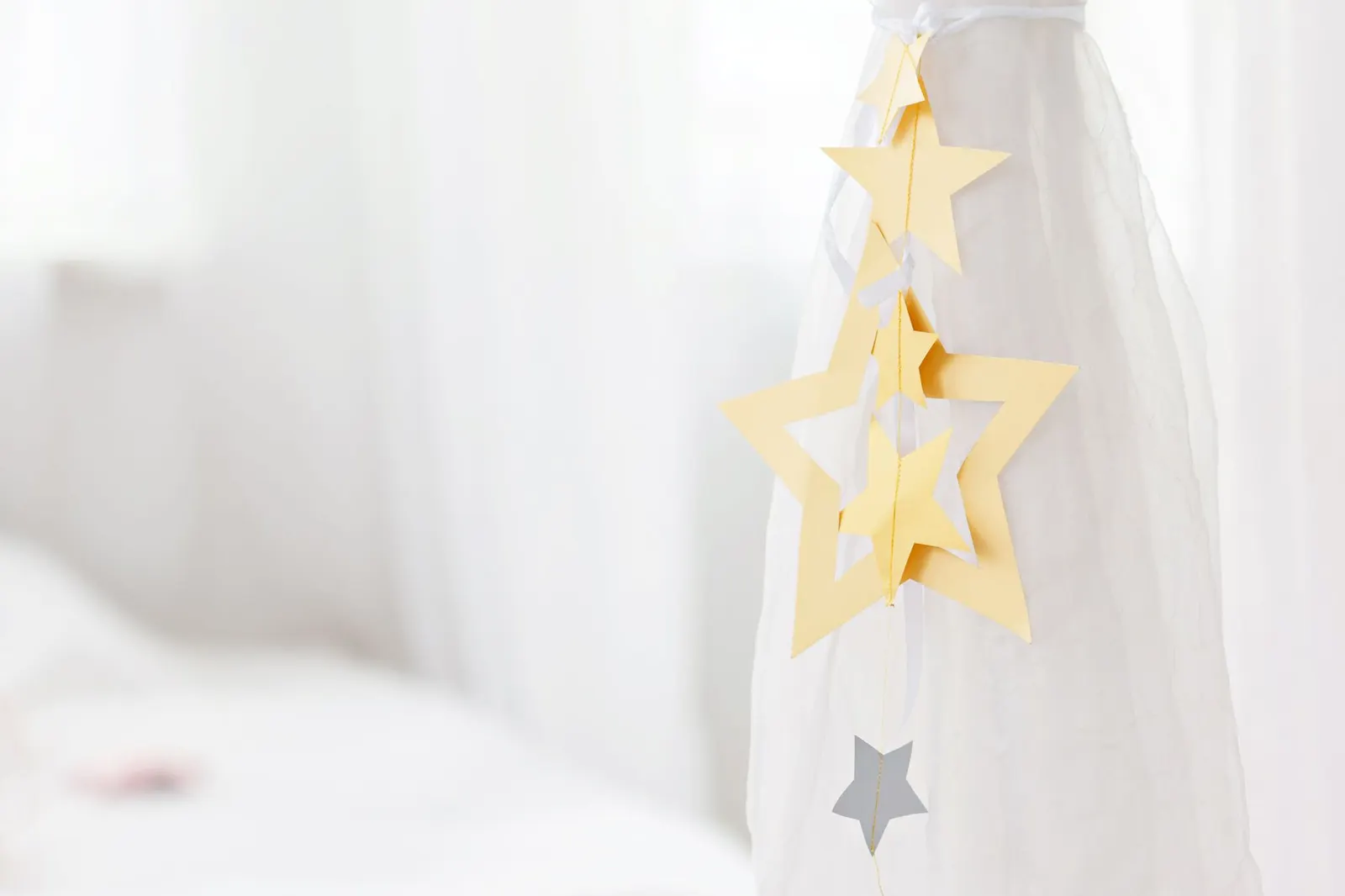 Blue and silver paper six-pointed stars strung on twine across a white wall