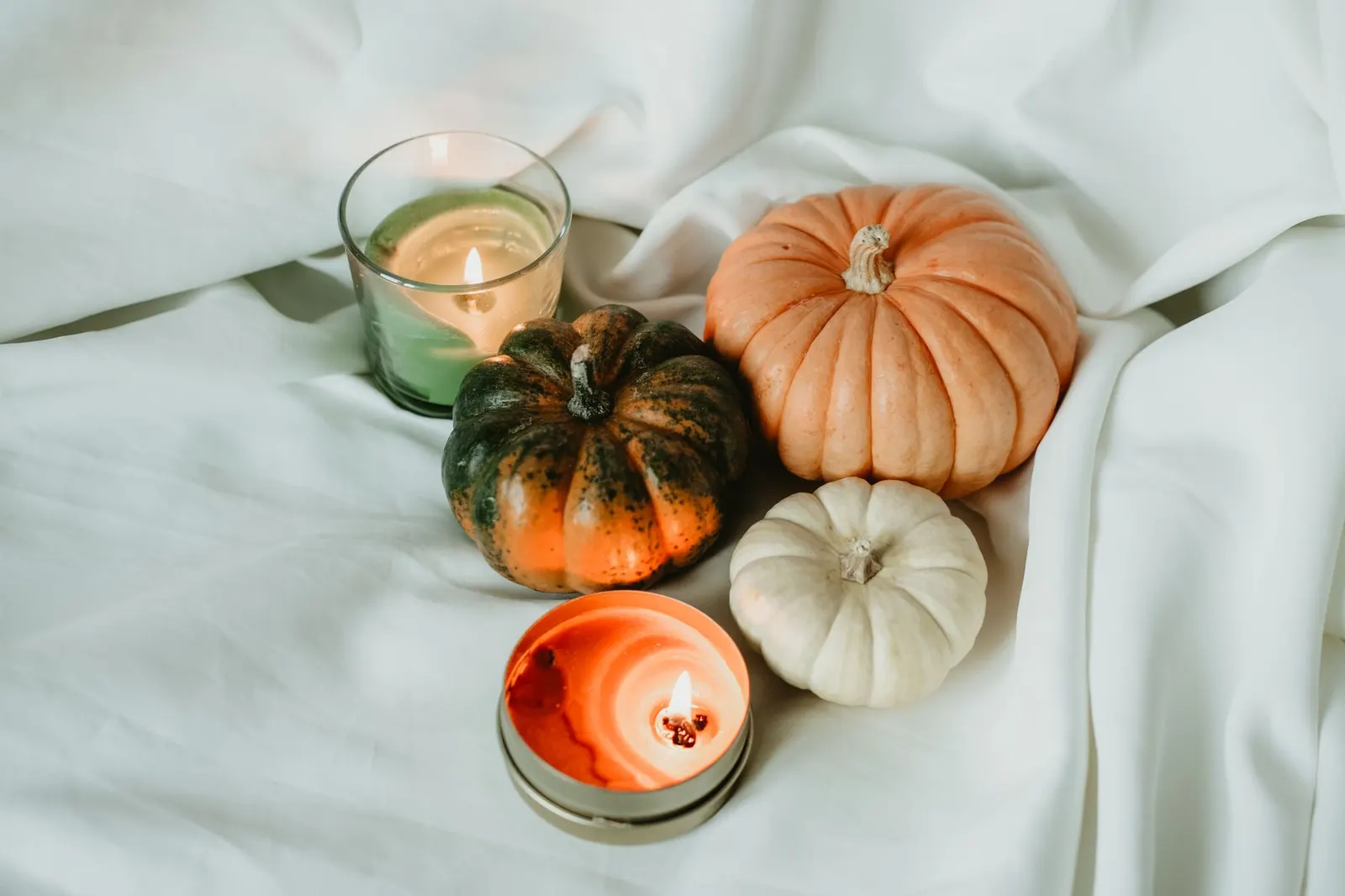 Low Thanksgiving centerpiece on a wood board with glass vases, LED pillar candles and faux pumpkins