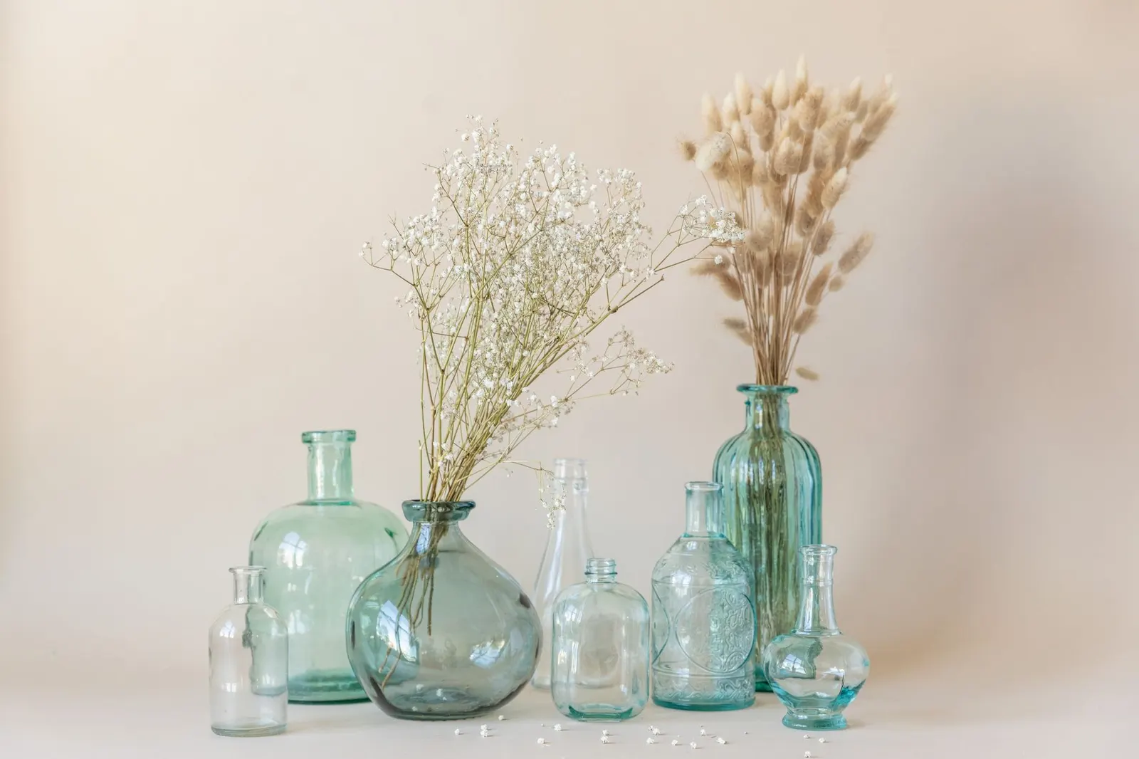 Clear glass vases and candle holders in several heights lined up on a wooden table