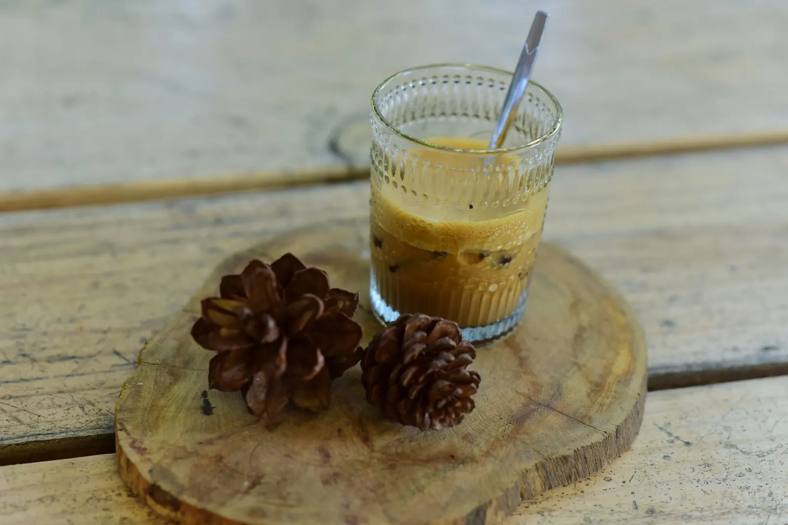 Pinecones next to a clear glass on a round wood board