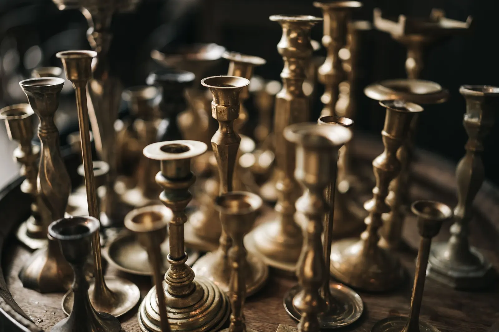 Brass candlesticks, amber glass bottles and a small wood box grouped on a thrift store shelf