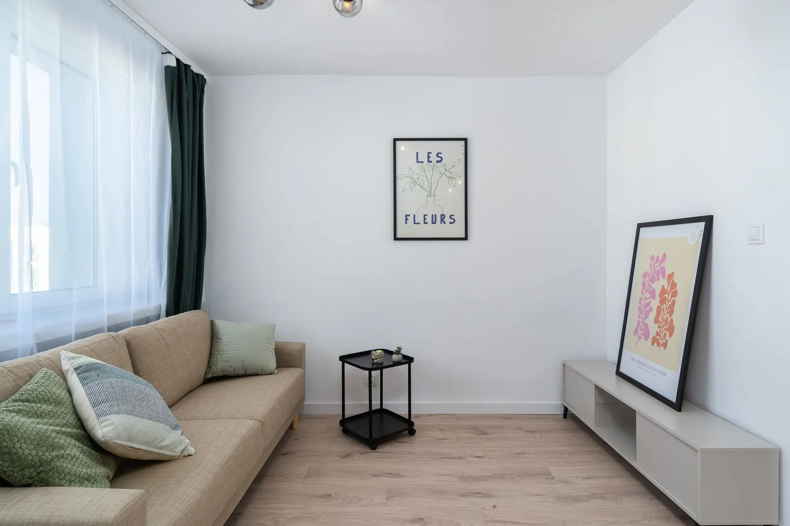 Small living room with a secondhand green sofa, a round wood coffee table, a jute rug and a floor lamp