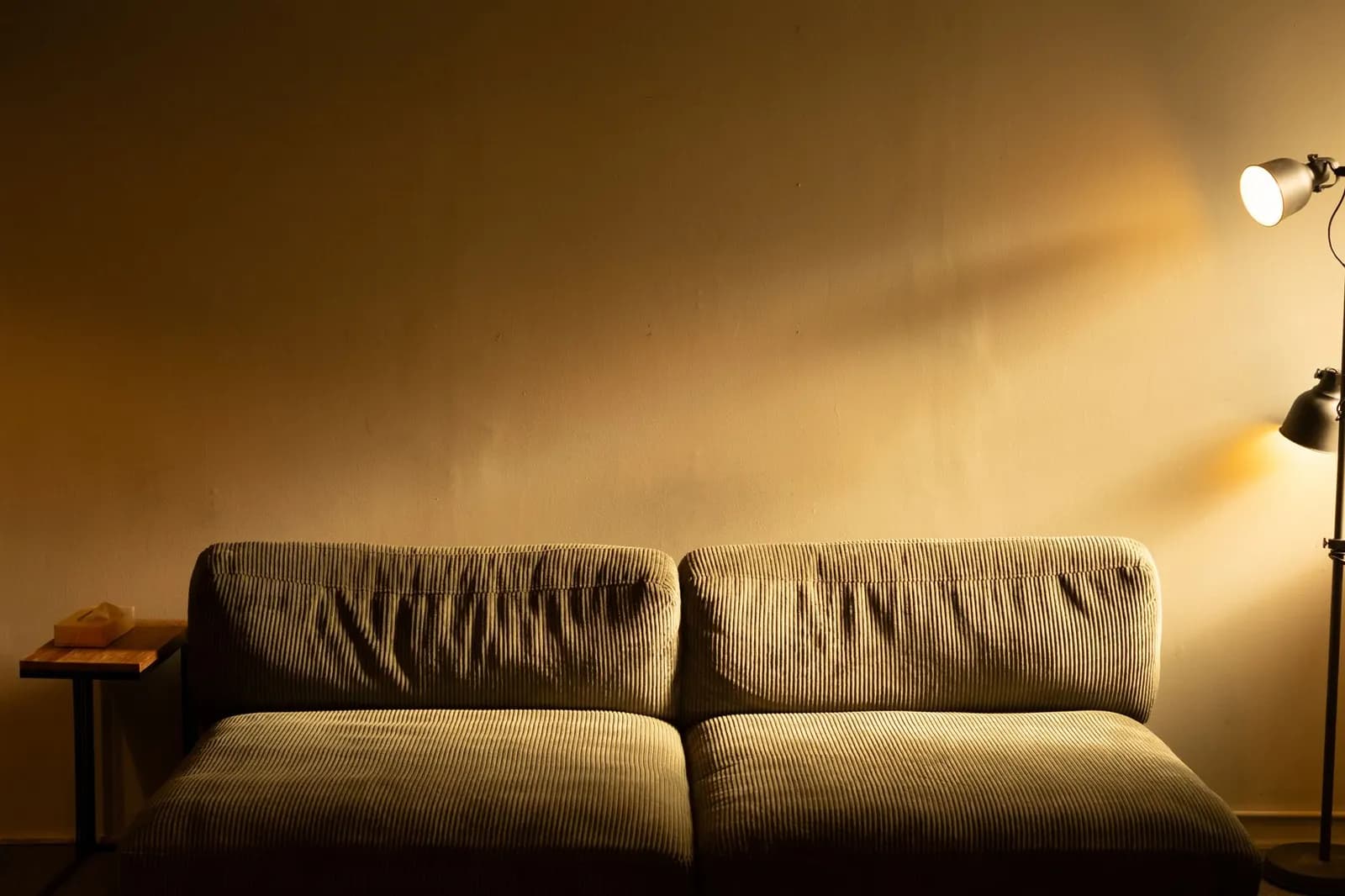 Living room at dusk lit by a floor lamp, a table lamp and a wall sconce with warm light