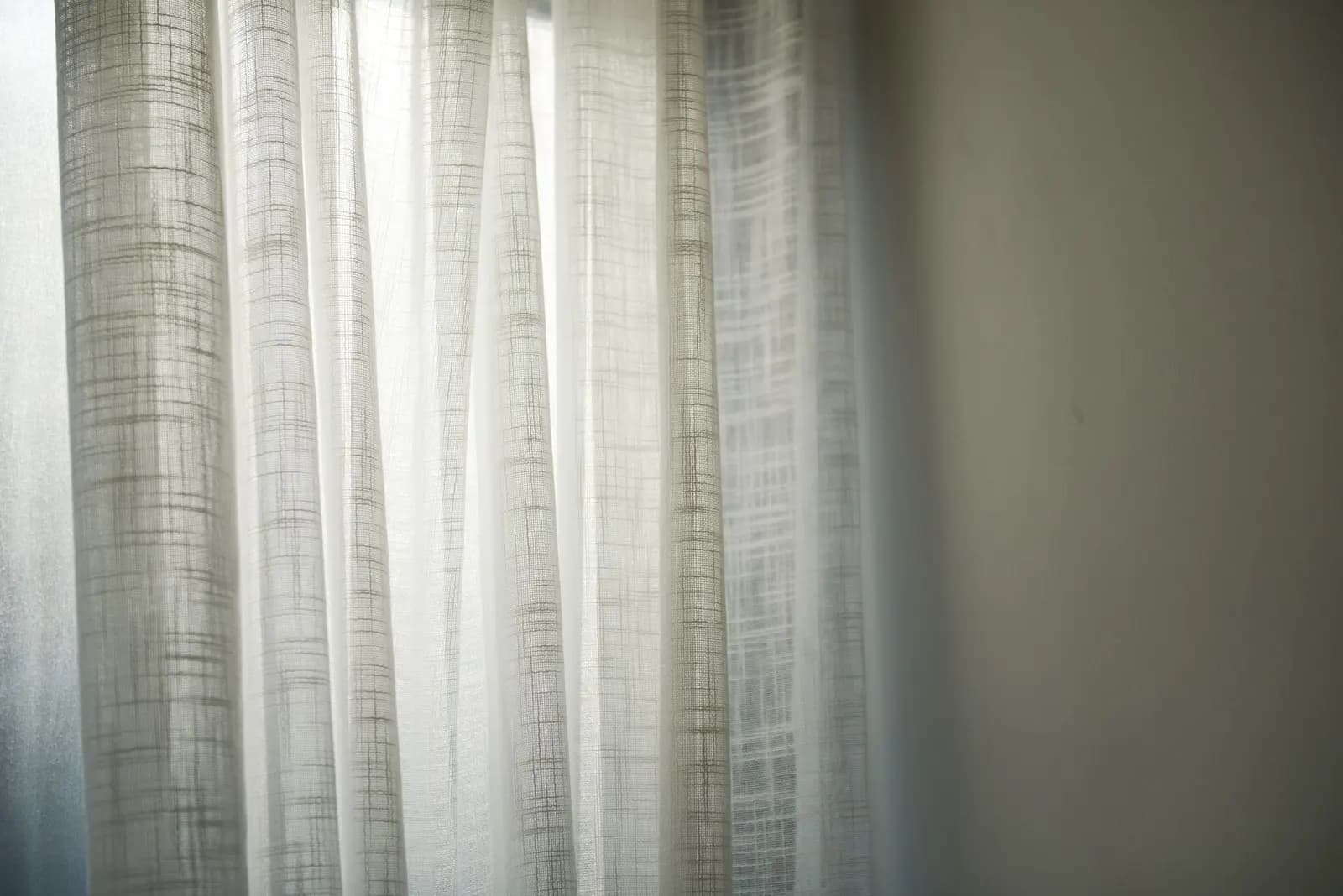 White sheer curtains on a wide rod letting soft daylight into a small living room