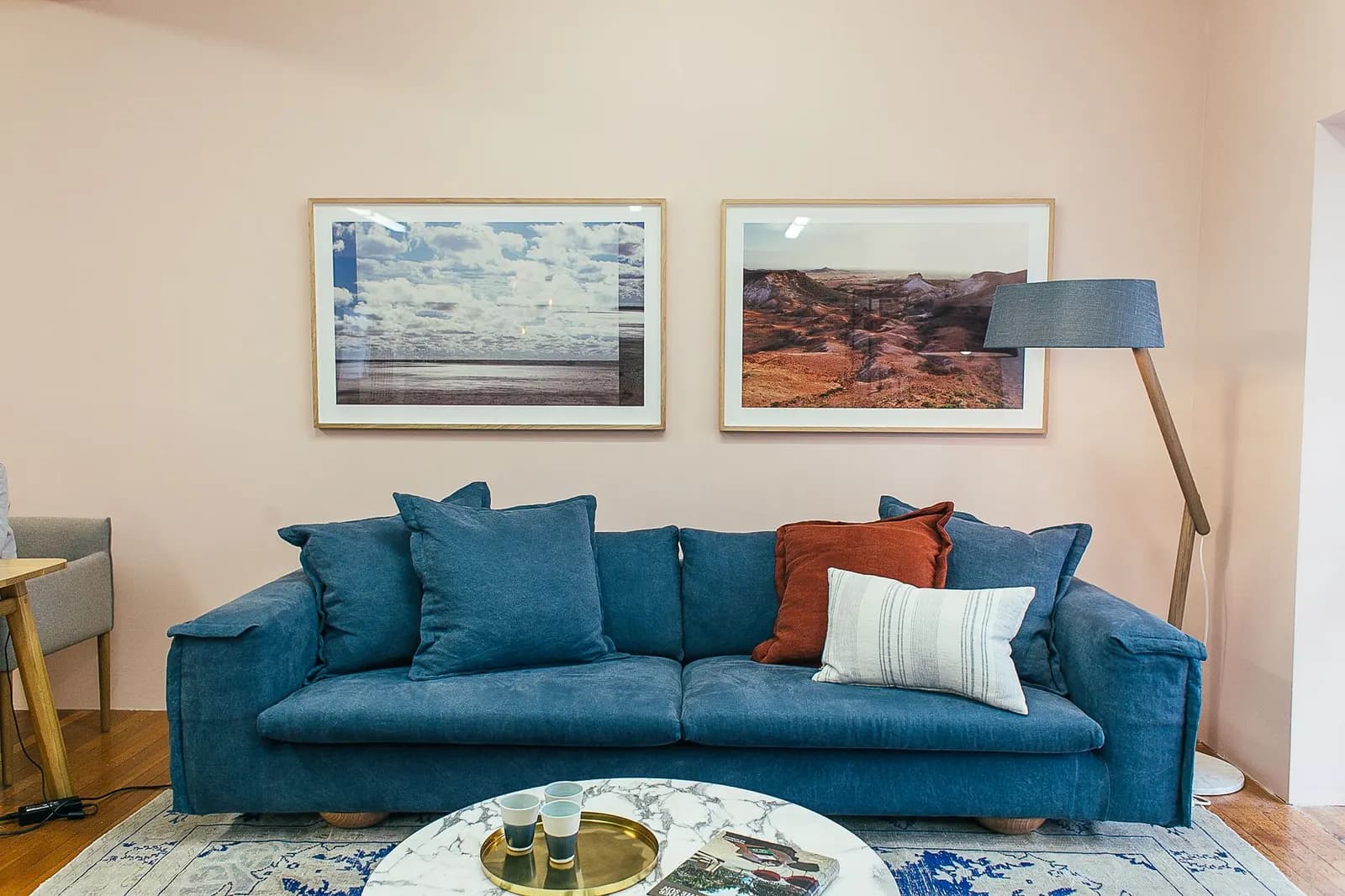 Two large black-framed prints hung side by side above a beige sofa in a bright living room