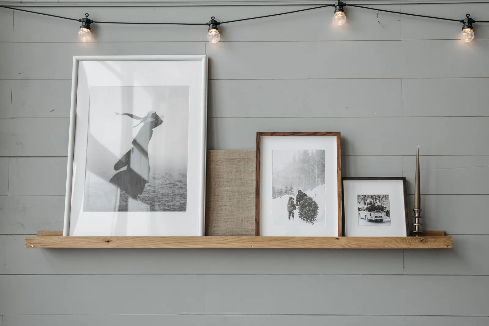 Framed prints and a small round mirror on a white apartment wall above a wooden console table