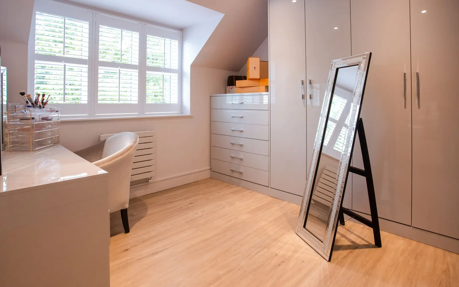 Tall wood-framed mirror leaning against a white wall next to a potted plant on a wood floor