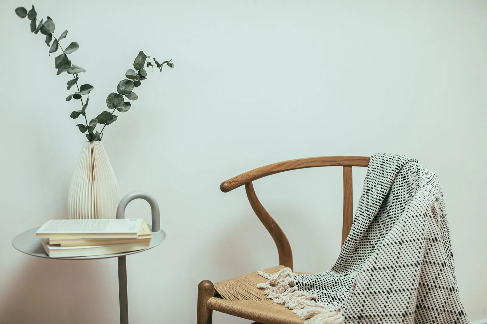 Wooden chair with a draped knit throw beside a small table with books