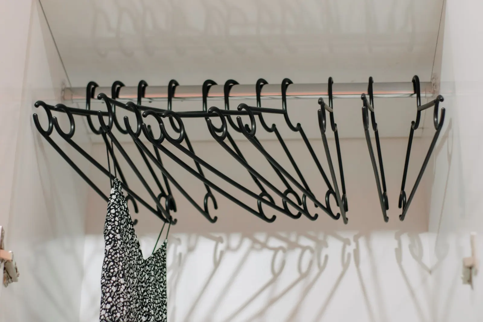 Small reach-in closet with matching slim hangers, folded sweaters in clear bins and shoes on a rack