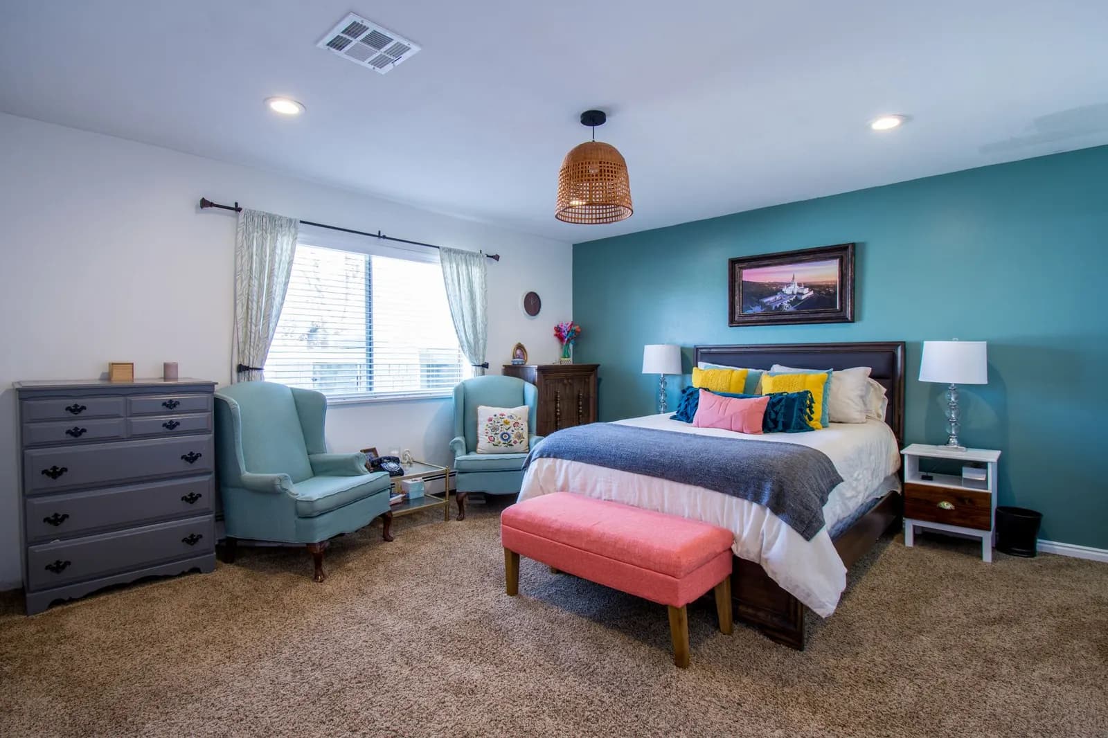 Modern bedroom with vibrant decor, featuring teal walls and comfortable furnishings.