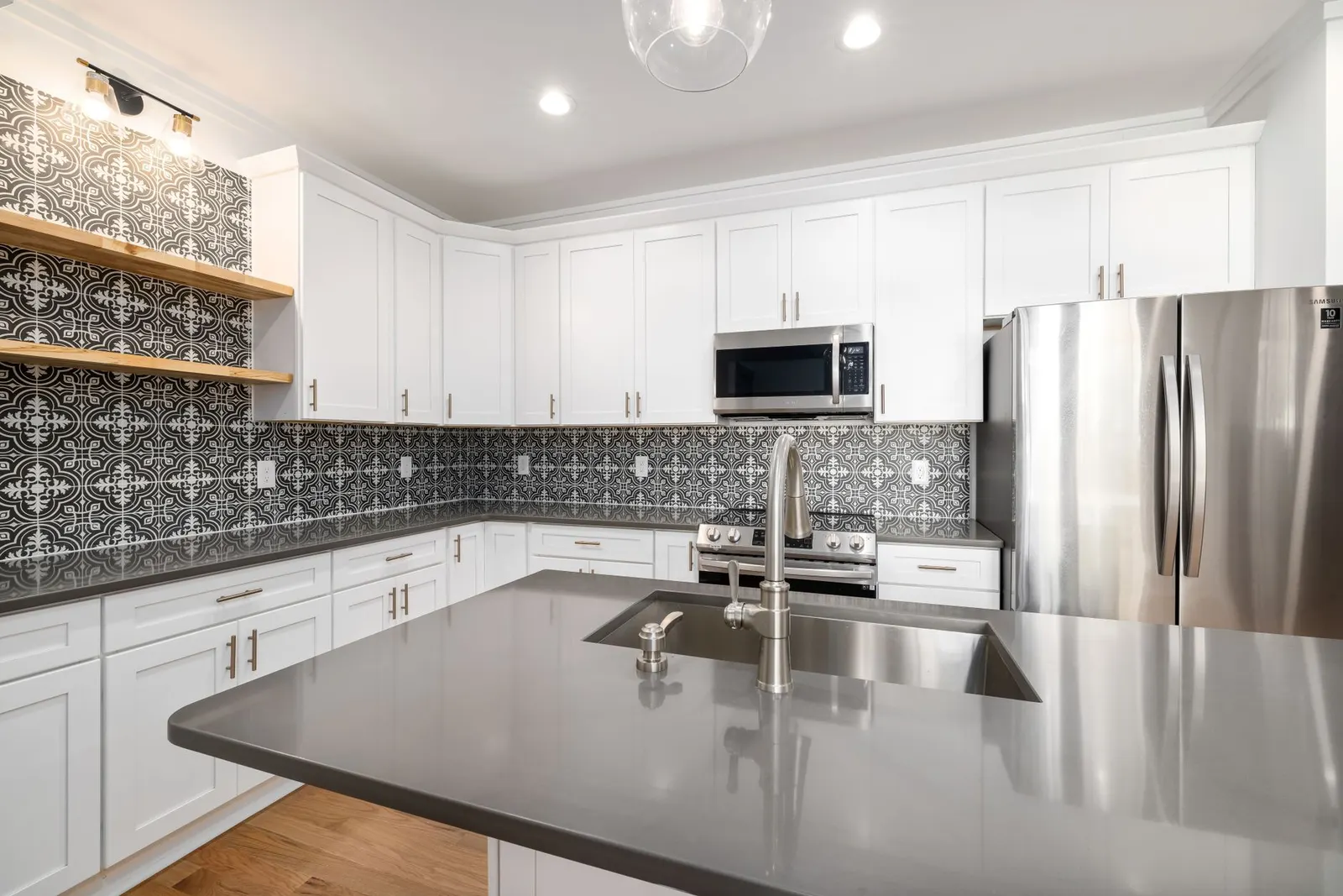 Stylish white kitchen featuring a geometric tile backsplash and stainless steel appliances.