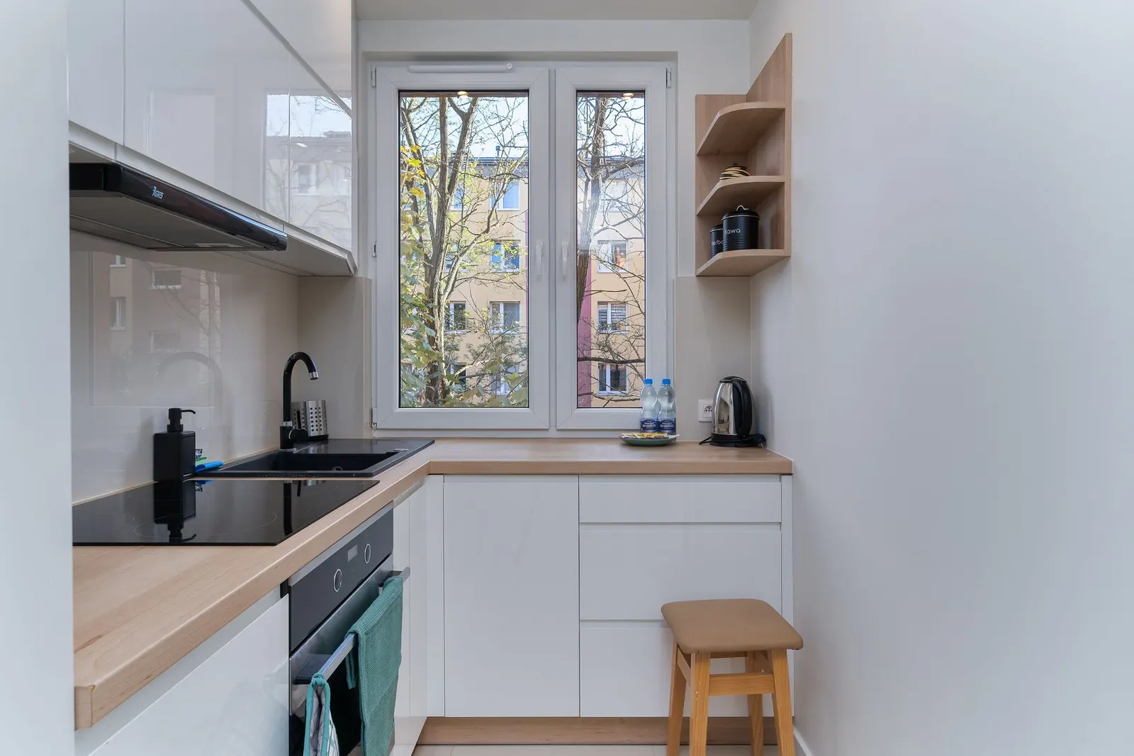 Compact and modern kitchen with sleek white cabinets and natural light.
