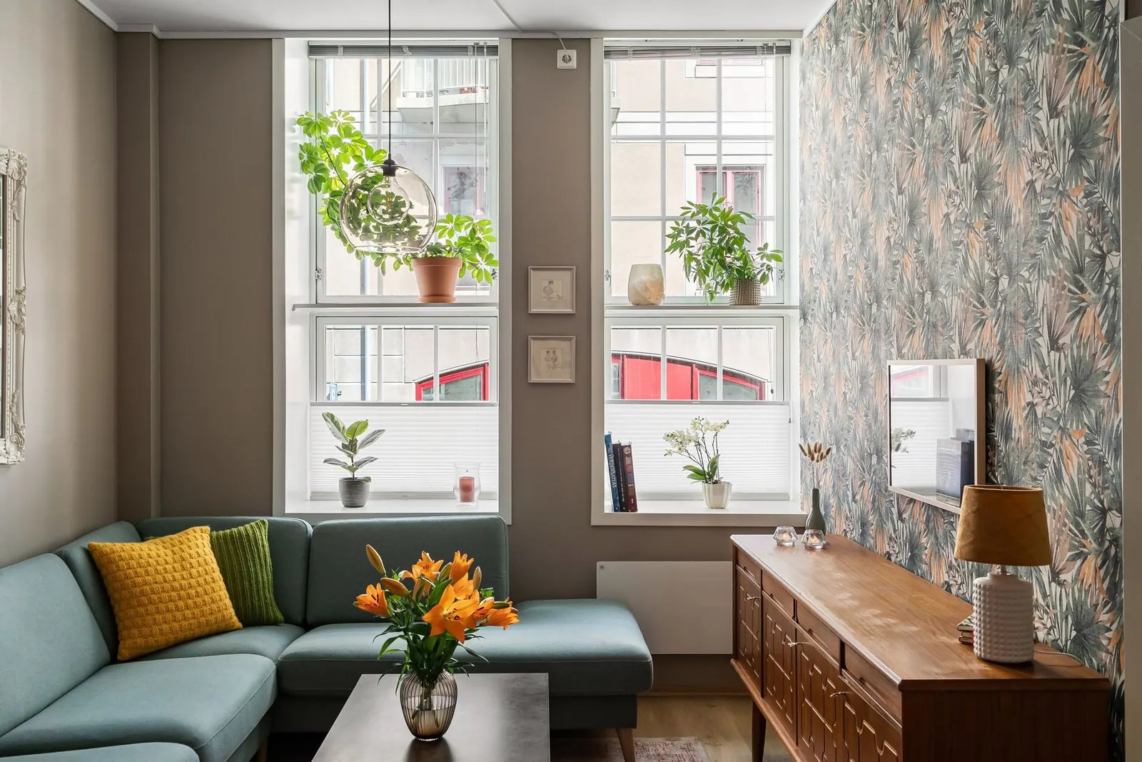 Bright apartment living room with a leaning mirror, plug-in wall lamp, linen curtains and a jute rug over carpet