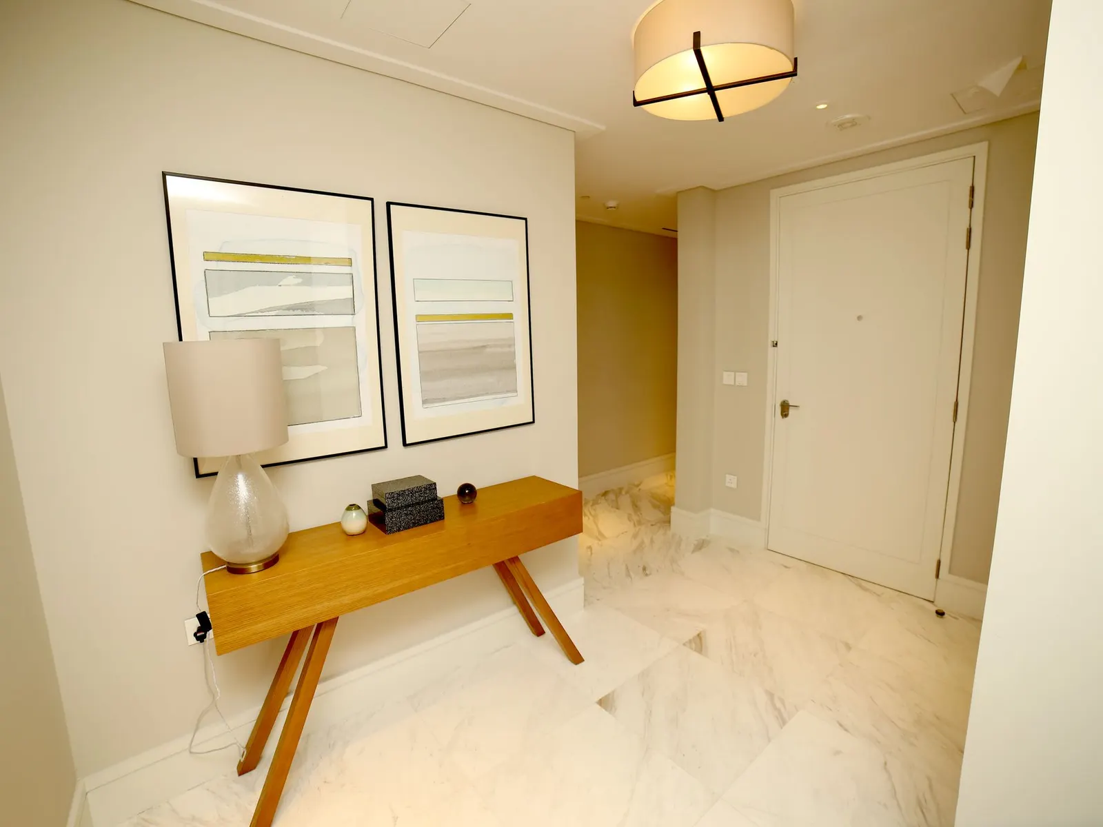 Framed art prints of different sizes leaning on a wooden console table against a white wall