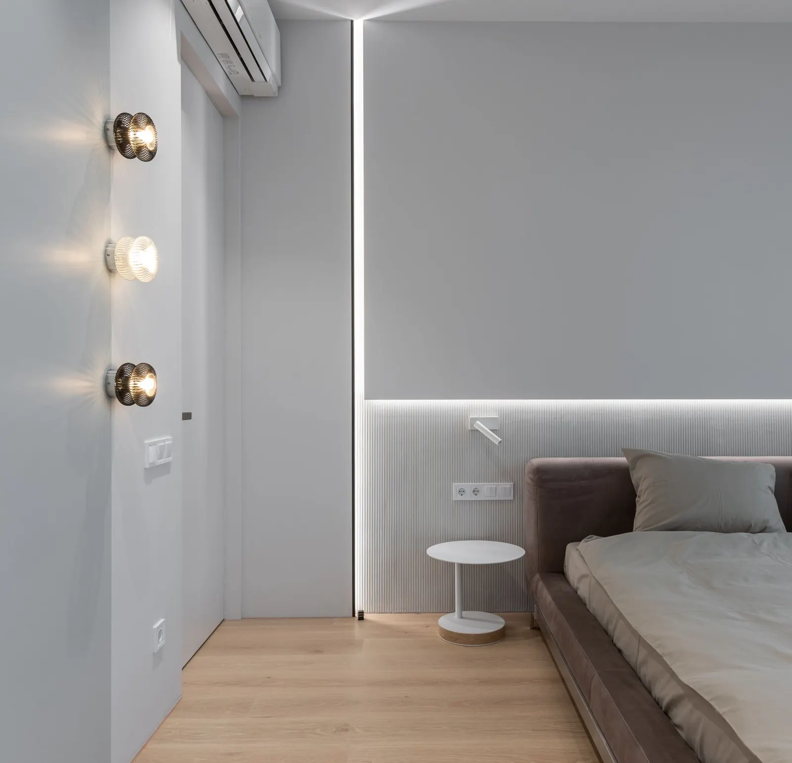Interior of modern minimal design of bedroom with gray bed at monochrome wall with built in light