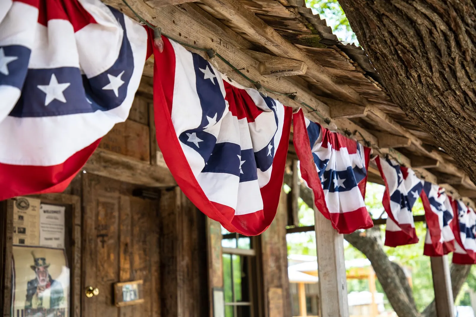 Front porch railing with red, white and blue paper bunting and a planter of white flowers
