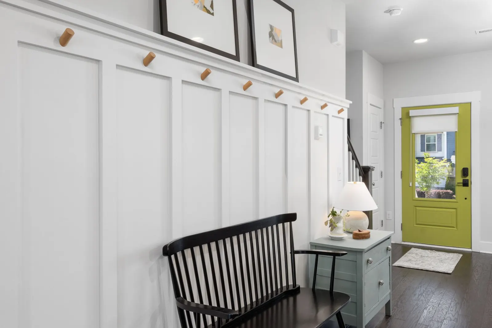 Stylish entryway featuring a green door, black bench, and decorative elements.